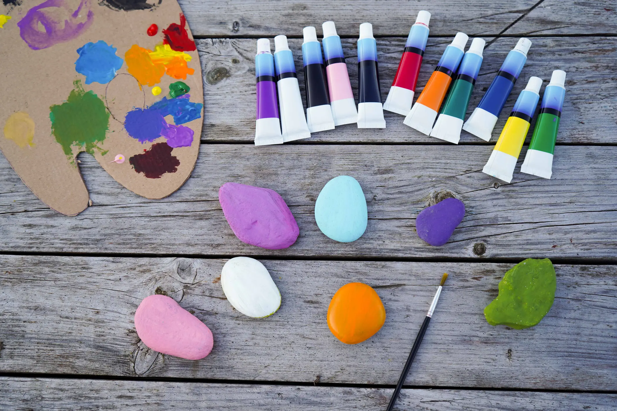 Paint tubes and colorful stones on table.